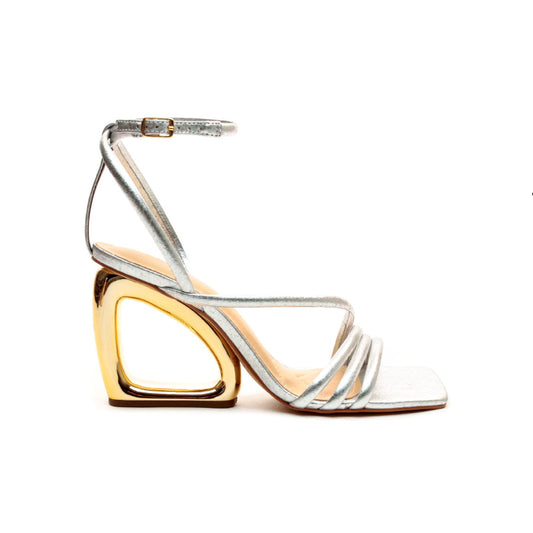Silver high-heeled sandals with gold heart-shaped heel on a white background
